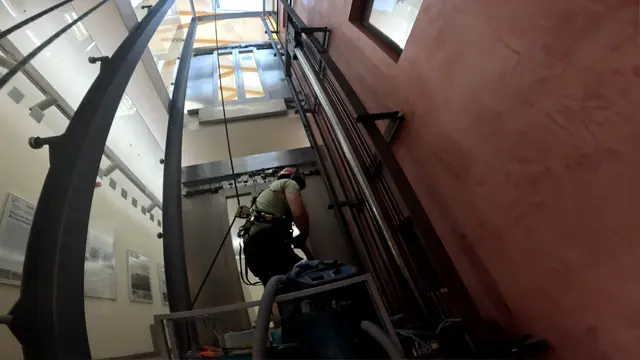 Výškový pracovník čistí výtahovou šachtu pomocí vysavače